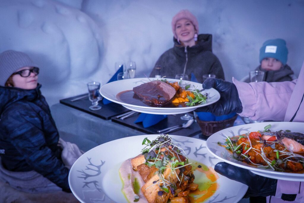 Tarjoilija tarjoilee ruokia perheelle Lumiravintolassa