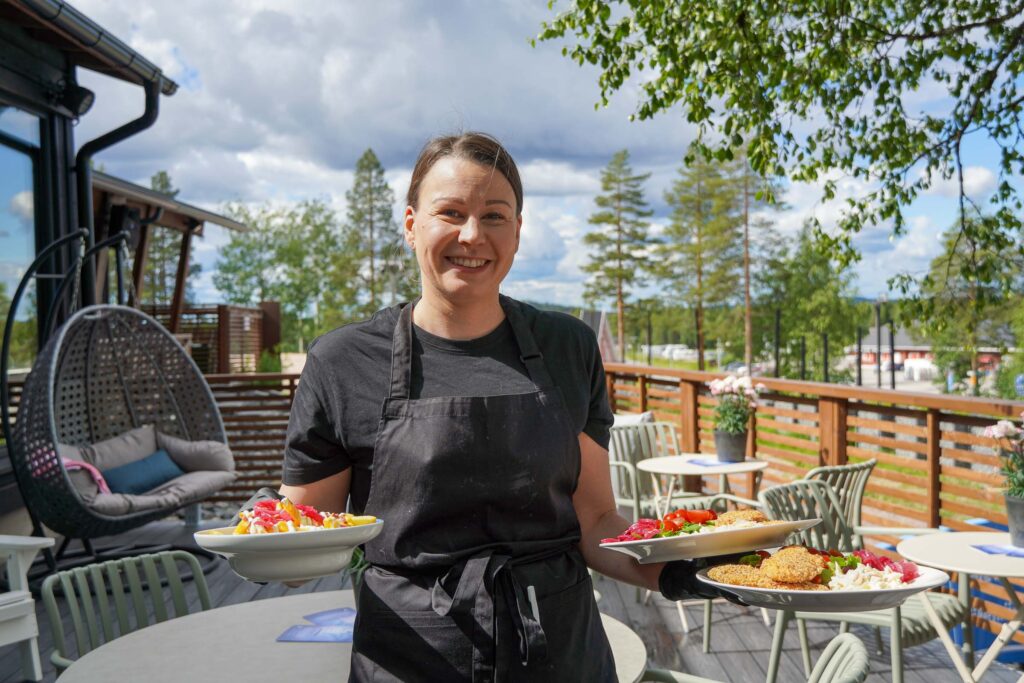 A member of the Café Ensilumi staff carrying lunch dishes on the terrace at Snowman World in Santa Claus Village in Rovaniemi.