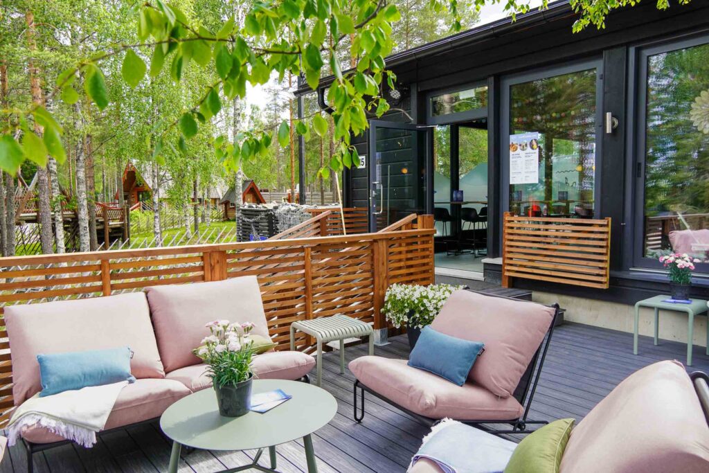 Exterior of Café Ensilumi with the entrance and outdoor terrace at Snowman World in Santa Claus Village in Rovaniemi.